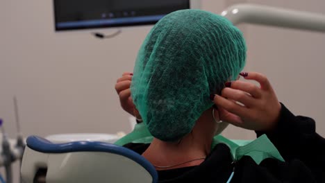 chica poniendo una gorra desechable y haciéndose cómoda en una silla dental