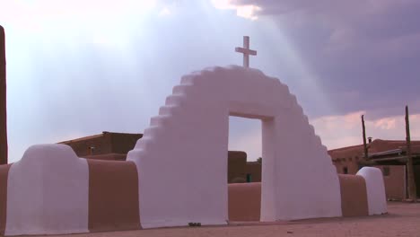 a christian cross glows against a heavenly sky at the taos pueblo