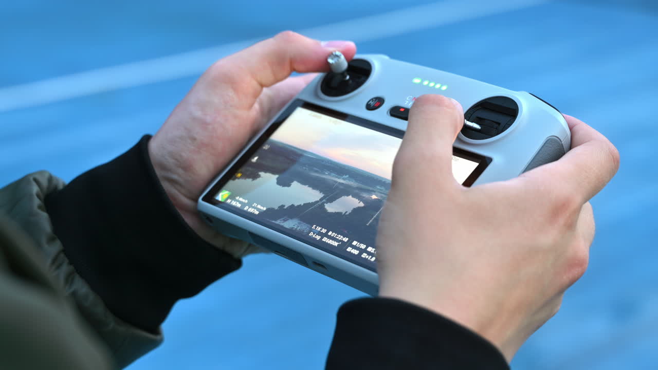 Man holding remote controlling the direction of a drone filming a park at sunrise