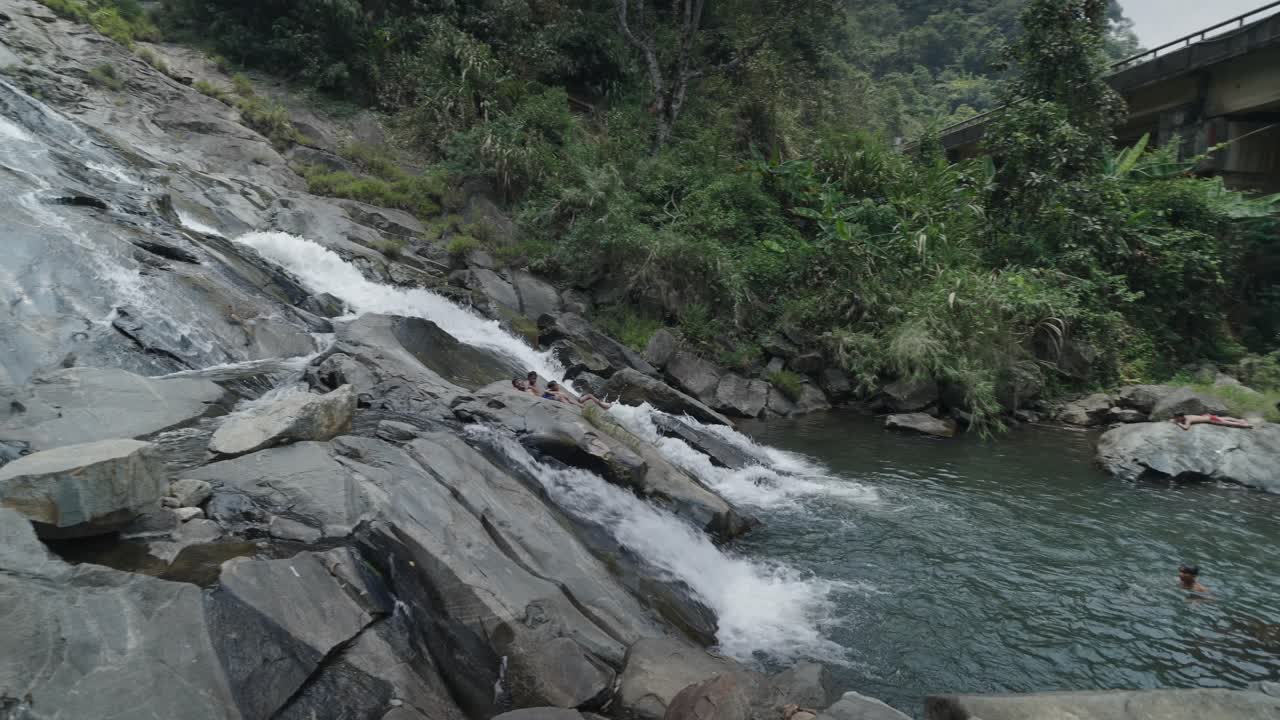 People enjoying a waterfall in a tropical forest