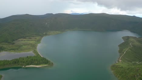 Lagoa-do-fogo,-a-crater-lake-surrounded-by-lush-greenery-and-mountains-in-azores,-aerial-view