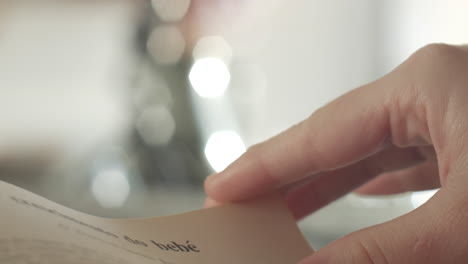 낮에 집에서 포르투갈어 책을 읽고 페이지를 넘기는 여성의 매크로 샷