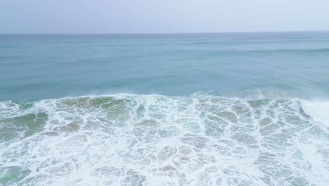 waves crashing on the shore in slow motion at aljezur, portugal, captured from above