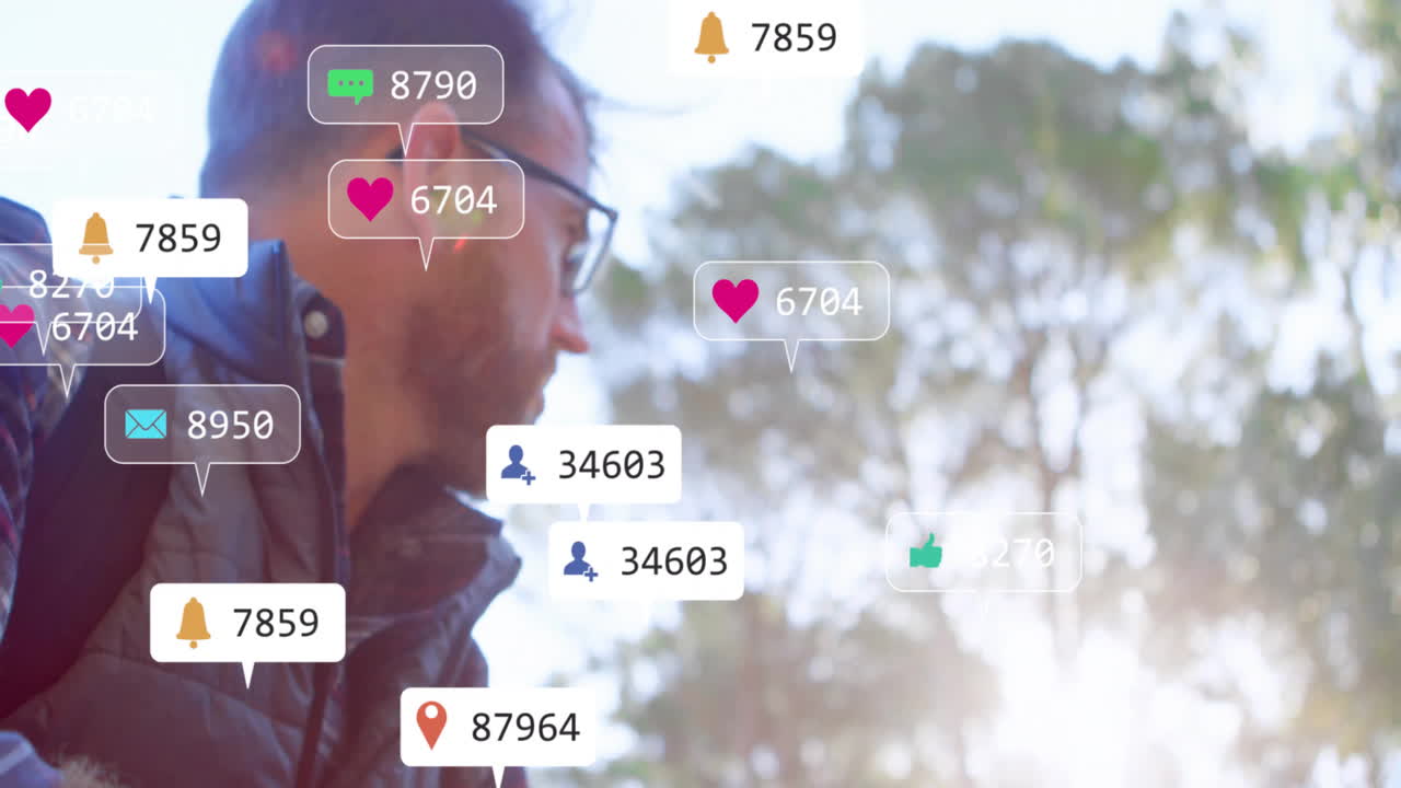 Man wearing glasses, backpack standing in woods, monitoring floating social icons for marketing