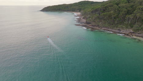 Noosa-Mainbeach-Turquoise-Ocean-Off-Beach-Headland-With-Boat-At-Sunrise,-4K-Drone-Slow-Motion-Australia