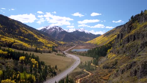 million dollar highway running through the rocky mountains lined with golden aspen trees in the fall to snowcapped mountains