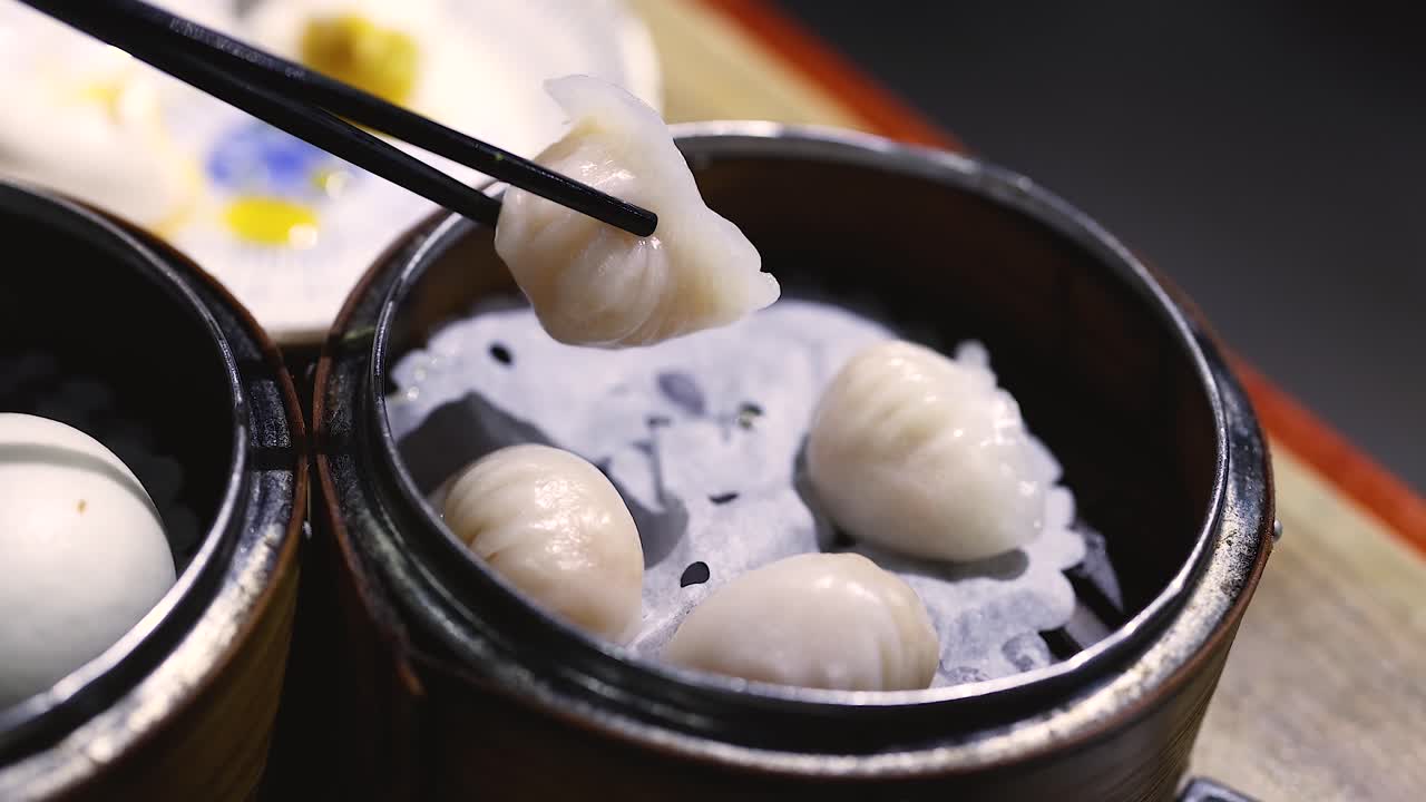 Chopsticks picking shrimp dumplings from steamer