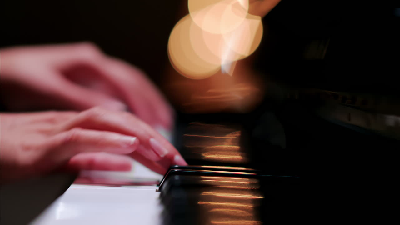 Close up of a woman's hands playing the piano with blurry lights on the background