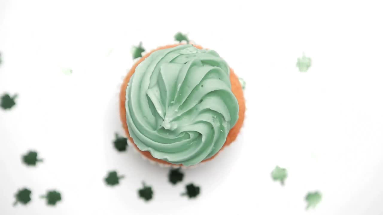 Cupcake di San Patrizio che ruota con coriandoli verdi a trifoglio che cadono