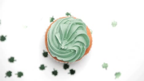 st patricks day cupcake turning with green shamrock confetti falling