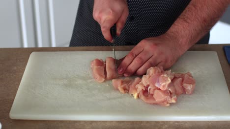 cortar el pollo en cubos sobre una tabla de cortar blanca 6