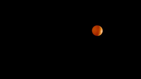 hand bouncing an orange ball in darkness