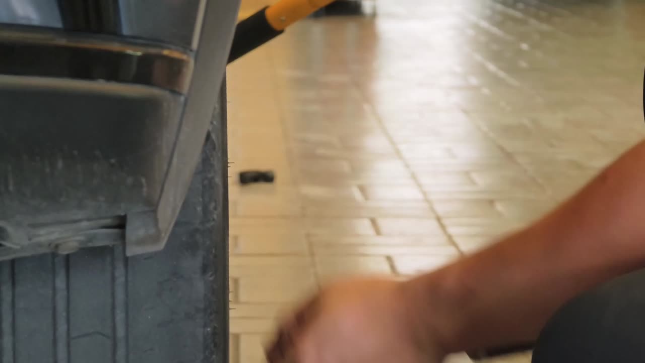 Mechanic's Hand Using Impact Wrench on Car Wheel