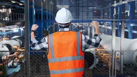 asian male engineer with safety helmet standing raising his hands celebrating working in factory manufacture of wind turbines