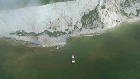 Top-down-close-view-Beachy-Head-Lighthouse,-white-cliffs,-foggy-sky-and-sea-taken-by-dji-mini-3-pro-drone-in-Eastbourne-England