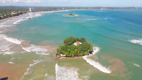 drone shot capturing taprobane island at weligama, sri lanka, with ocean waves and coastal landscape