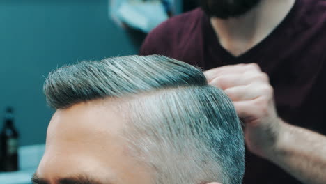 Barber-doing-hairstyle-with-comb.-Close-up-of-male-hands-of-hairstylist