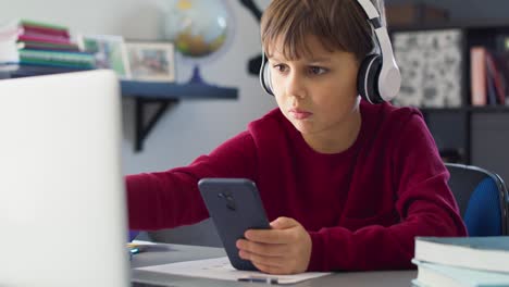 handheld video of boy playing on the phone during homeschooling