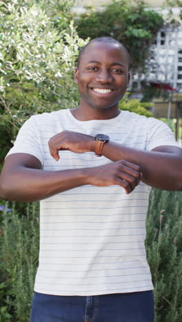 vertical video: smiling man standing with arms crossed in garden, enjoying outdoor time
