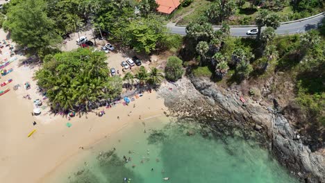 drone footage captures a vibrant beach scene in phuket, thailand, showcasing turquoise waters, sandy shores, and lush greenery
