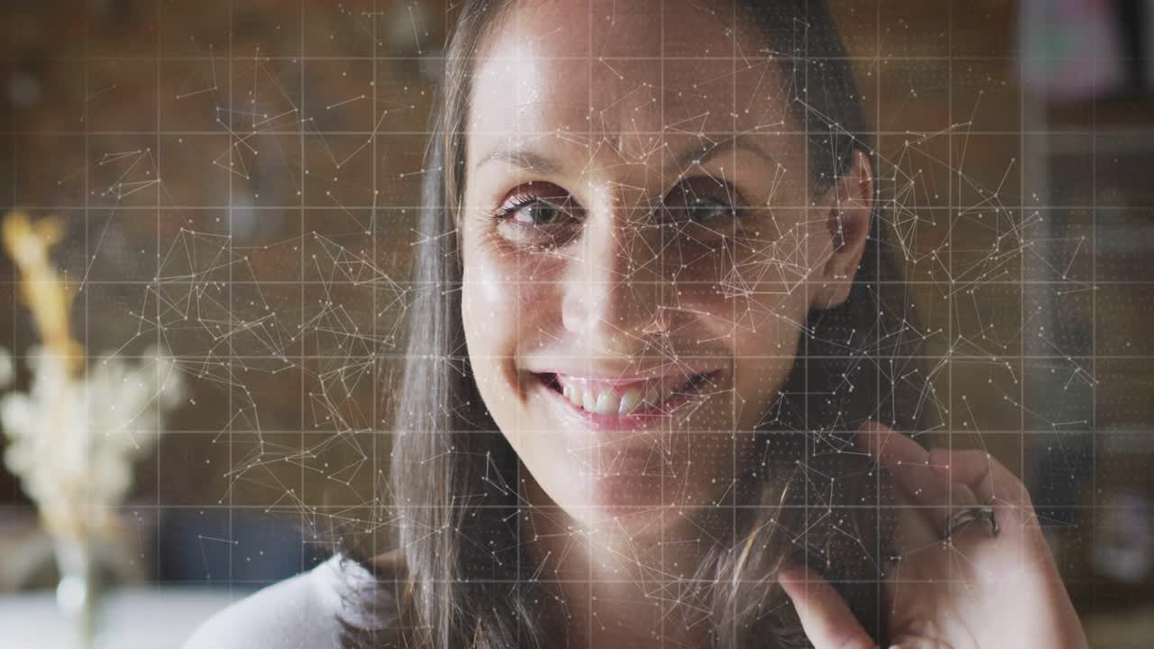 Donna di mezza età seduta in ufficio, sovrapposizione di griglie, scorrimento di codice, sorriso, analisi dei dati