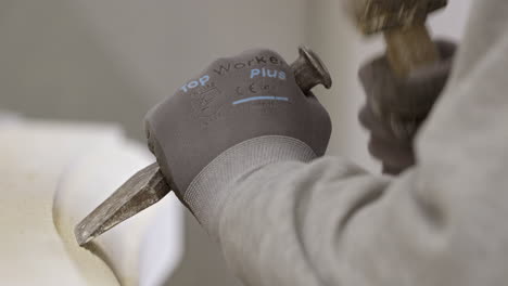 craftsman working on historic stone element with hammer and chisel