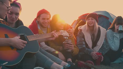 Fröhliche-Wanderer-Hören-Gitarre-Und-Sitzen-Am-Lagerfeuer-Im-Lager