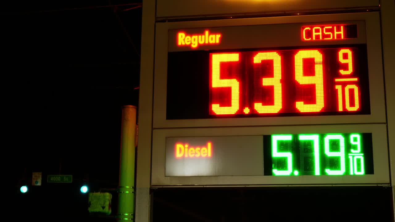 Gas station prices LED flashing light up sign for regular and diesel fuel at night over 5 dollars per gallon credit and cash price, during 2021 2022 war time recession, ground up shot no background