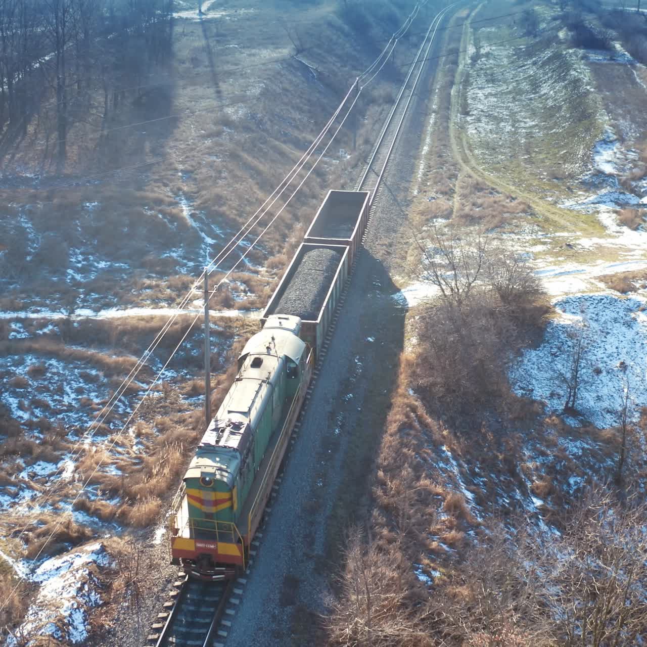 View from above on a freight train. Small cargo train moving on railroad in a sunny winter day. Aerial view.
