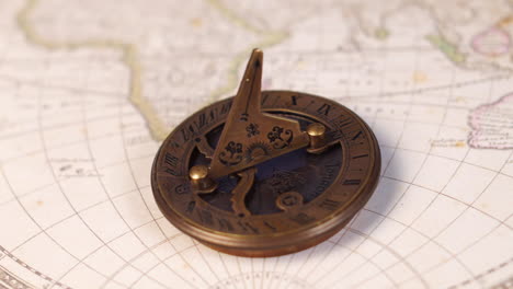 an antique nautical sun dial on ancient world map