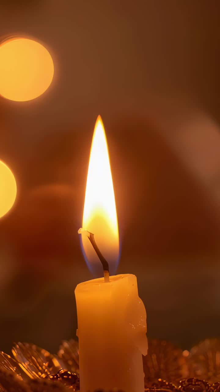Video verticale: clip che inizia, candela gialla che tremola con stoppino bruciacchiato e gocce di cera, bokeh