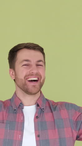 portrait of a happy man in simple clothes smiling and raising his hands up to the camera portrait of a happy man in simple clothes smiling and raising his hands up to the camera isolated on green background