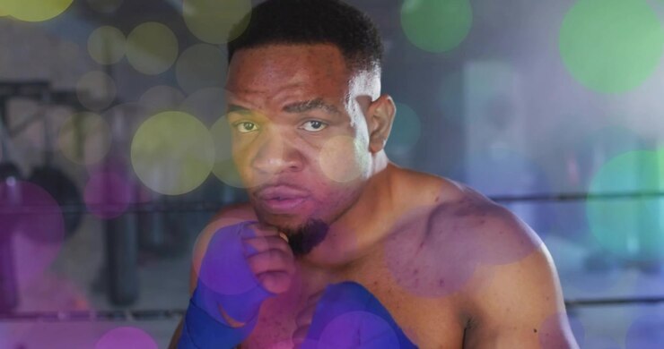 Pugile che cambia posizione e fissa lo sguardo, sferrando una combinazione di due pugni sul ring da boxe con effetto bokeh sfocato