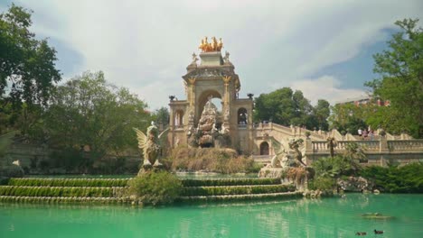 Atemberaubendes-Video-Eines-Mädchens-In-Grünem-Kleid-Und-Strickmütze,-Das-Die-Cascada-Monumental-Im-Parc-De-La-Ciutadella,-Barcelona,-Spanien,-Beobachtet