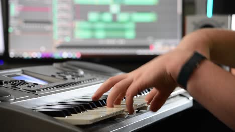 shot of a musician's hands playing chords on a keyboard in a home recording studio