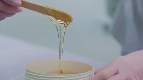 liquid sugar for skin epilation. close up shot. depilation and beauty concept - sugar paste or wax honey for hair removing with wooden waxing spatula sticks