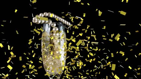 Golden-confetti-falling-over-pearl-beads-falling-in-champagne-glass-against-black-background