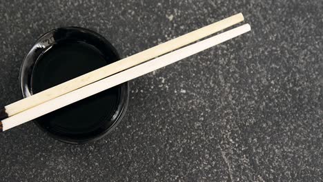 chopsticks and soy sauce on black stone slate