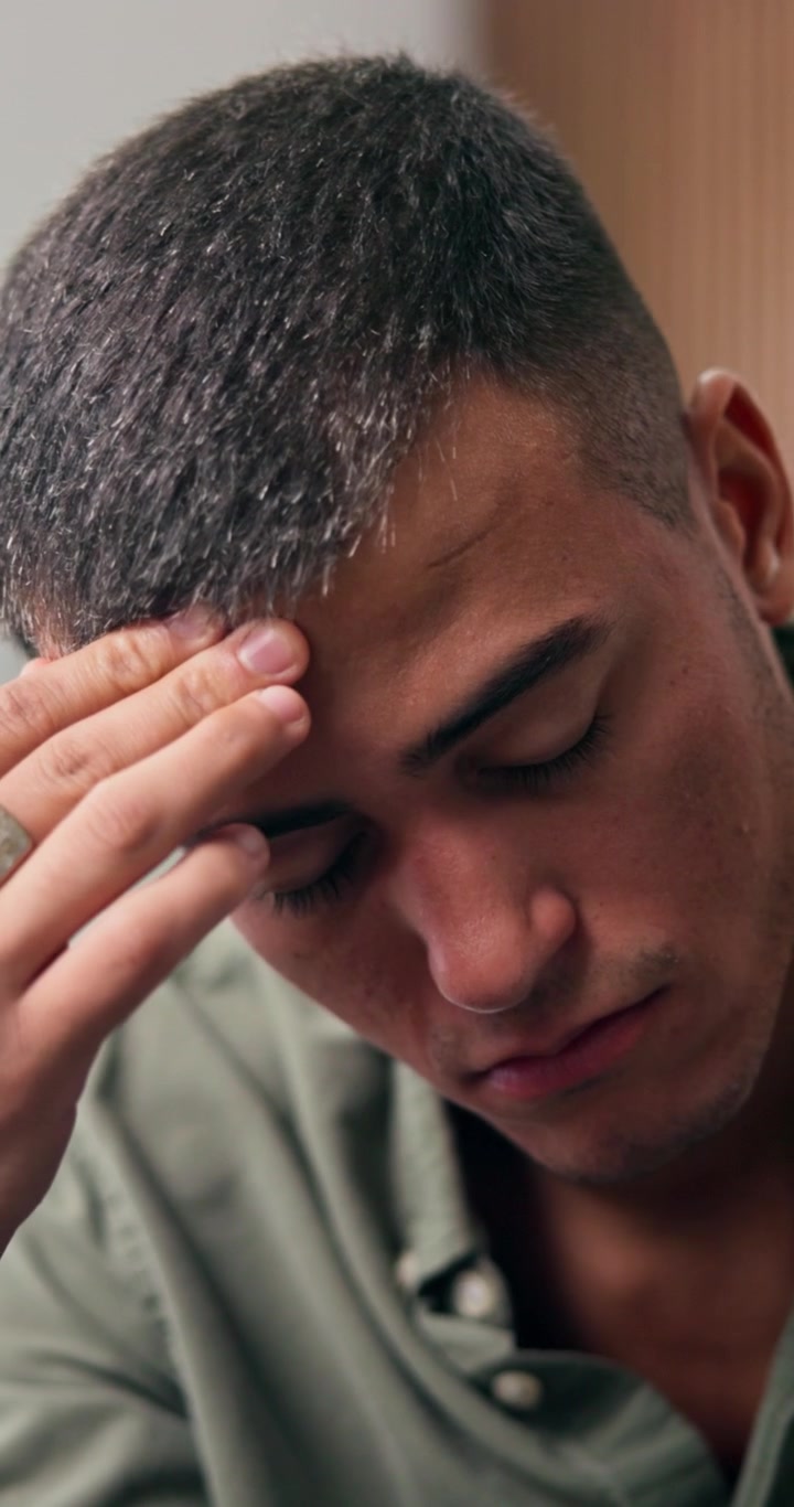 Giovane uomo stressato che si strofina la fronte pensieroso