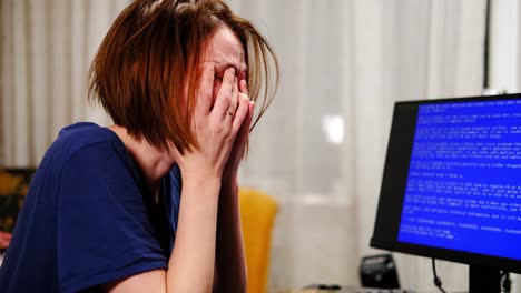 la mujer está frustrada frente a la pantalla azul de la computadora en casa. avería, virus en la computadora. agotamiento, concepto de agotamiento.