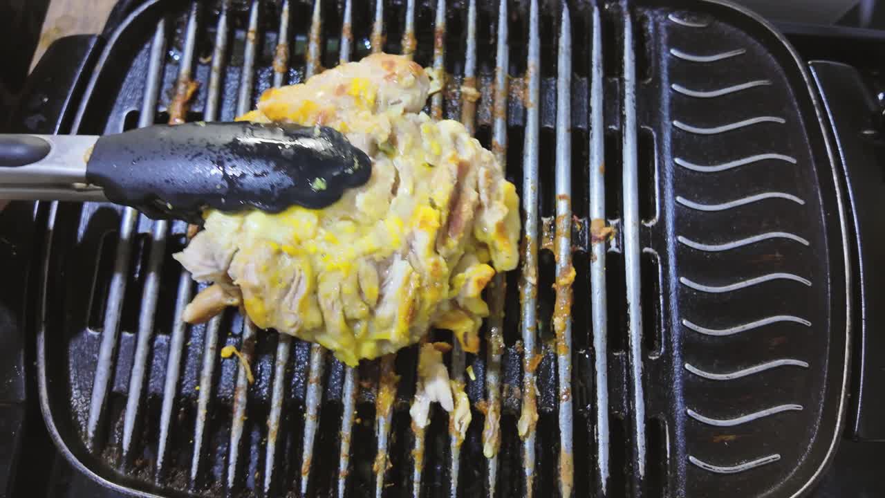 Turning chicken on the grill with tongs. Healthy food, top down shot