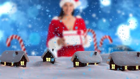 Animation-Von-Schnee,-Der-über-Eine-Winterlandschaft-Mit-Häusern-Und-Einer-Kaukasischen-Frau-Im-Weihnachtsmannkostüm-Fällt