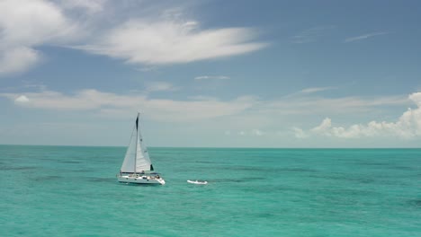velero con lancha motora conectada en el mar caribe turquesa, vista aérea de drones