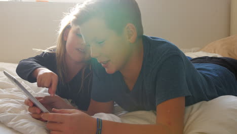 Children-Lying-On-Bed-Using-Digital-Tablet