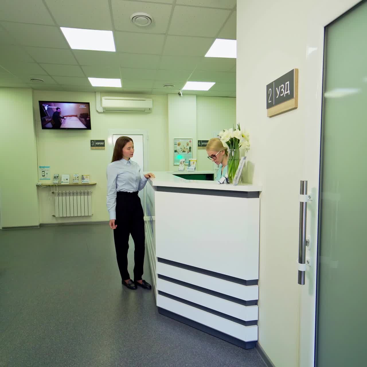Patient at receptionist in modern clinic. Young woman takes the results of her diagnostic and goes away from hospital.