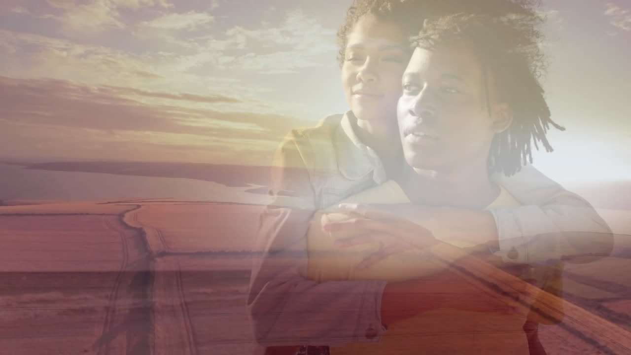 animación de una pareja afroamericana sonriente abrazándose en la playa sobre el paisaje del atardecer