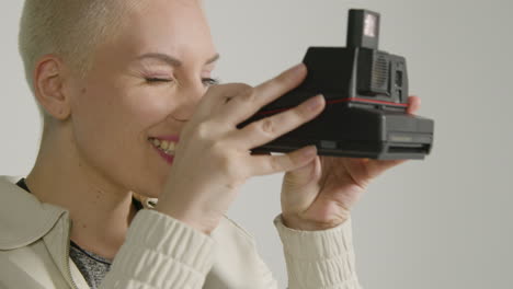 side view of a female photographer posing with instant film camera 01