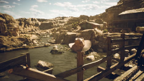 cowboy hat hanging on a fence in the desert