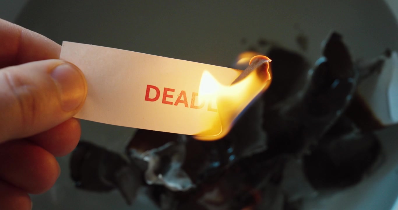 Close-up of a paper strip with the word “deadline” burning, symbolizing time pressure, work stress, urgency, project risk, and burnout.