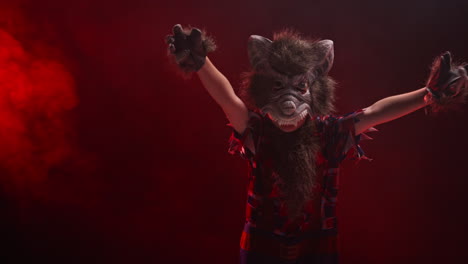 Studio-Shot-Of-Child-Dressed-Up-In-Werewolf-Monster-Costume-Trick-Or-Treating-At-Halloween-With-Red-Smoke-Background-Lighting-Scaring-People-1